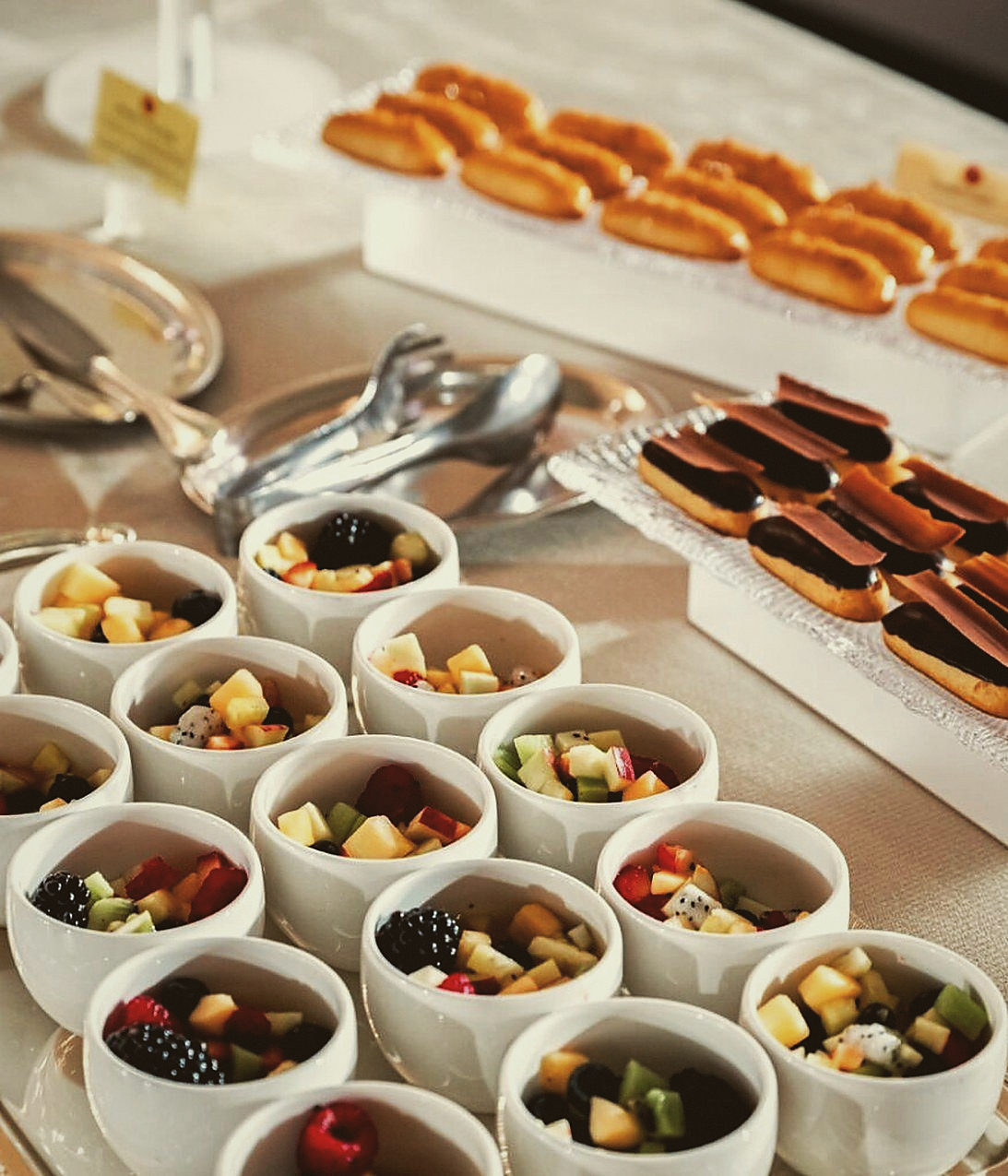 A coffee and sweets station with fruit cups and pastries